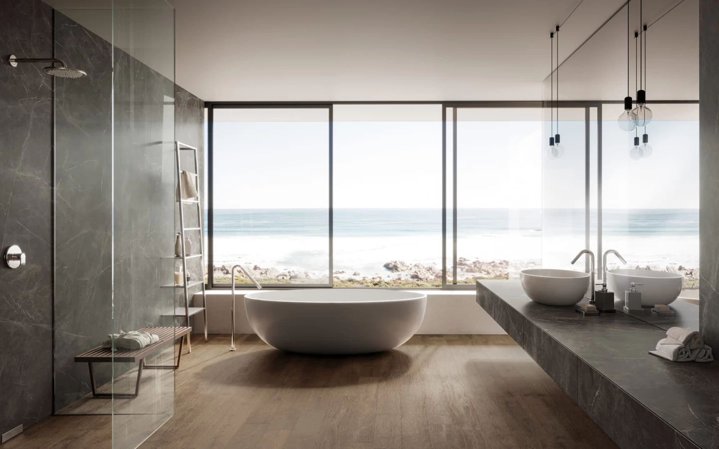 A spacious, modern bathroom overlooking the ocean through floor-to-ceiling windows. The flooring is dark wood-look tile, while the shower and floating vanity countertop are clad in dark grey, lightly veined Grey Stone Porcelain.