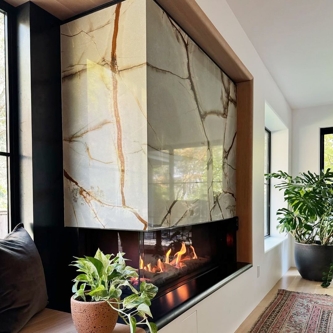 A modern fireplace feature encased in a corner-wrapping stone with thick, prominent rust and gold veining against a translucent white or light beige background