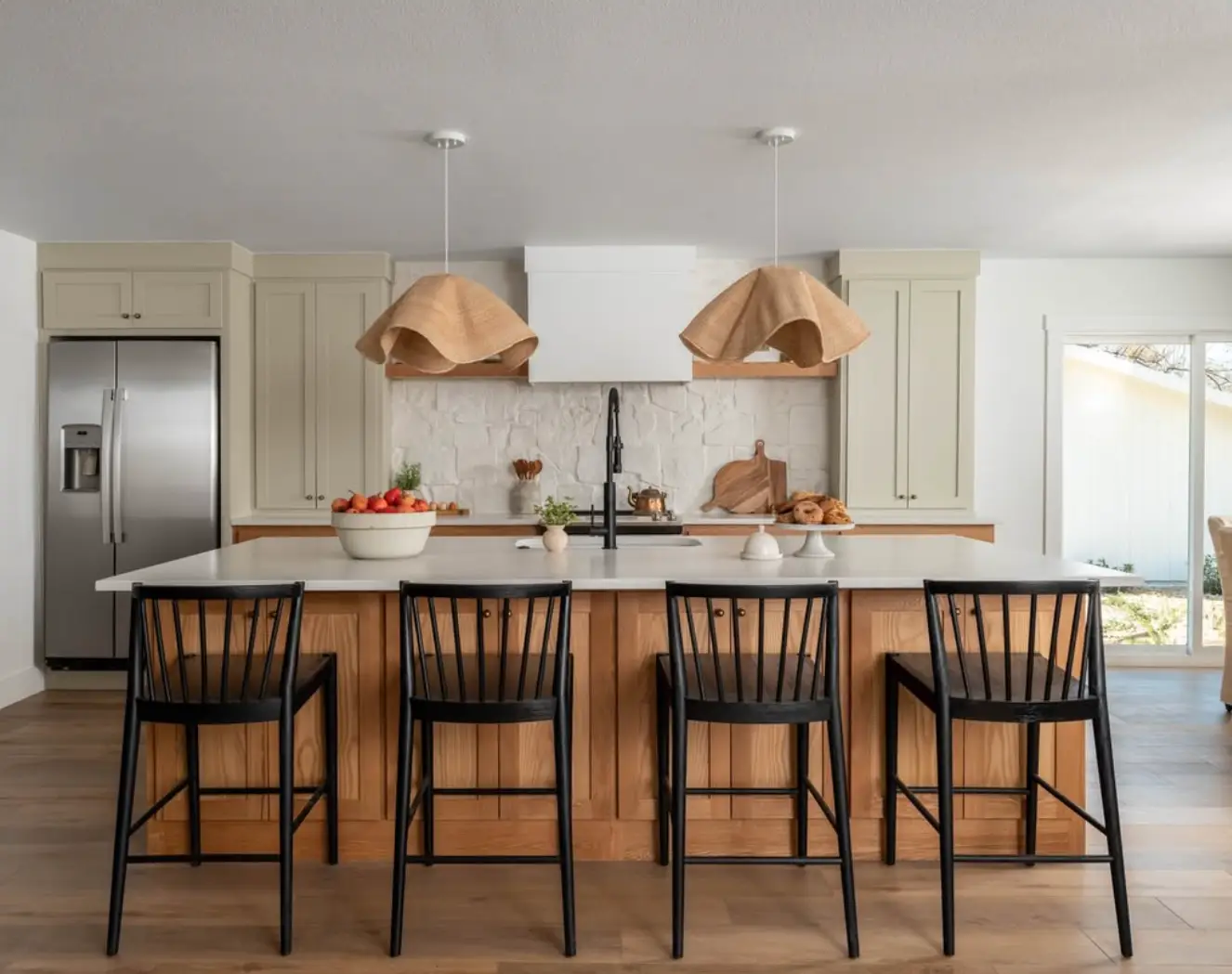 Modern farmhouse kitchen with white quartz countertop, natural wood island and black Windsor stools