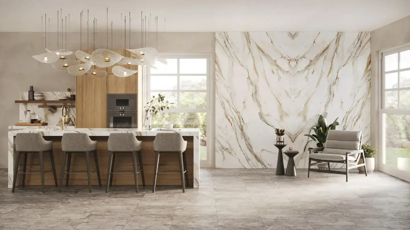Modern kitchen and lounge area with marble accent wall, kitchen island, bar stools, pendant lights, and a cozy armchair.