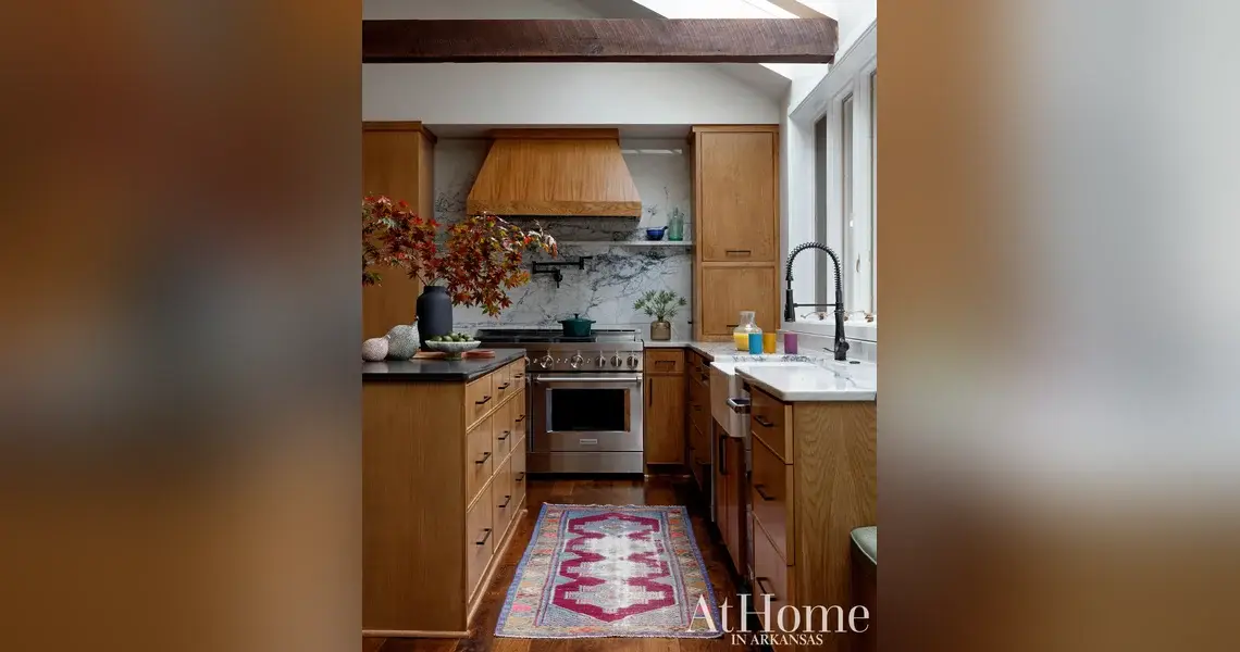 Kitchen with stained oak cabinetry, a wood range hood, a quartzite backsplash with pot filler, a professional range, and a vintage runner rug.