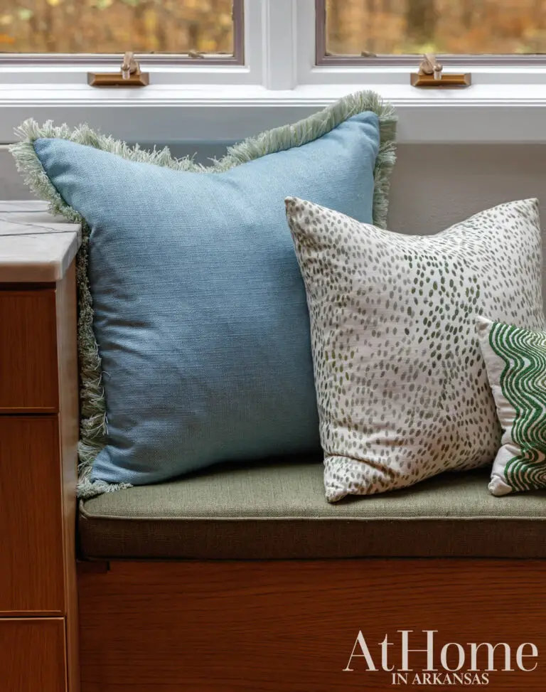 Built-in bench at the breakfast table with a green cushion and blue, speckled, and green patterned pillows.
