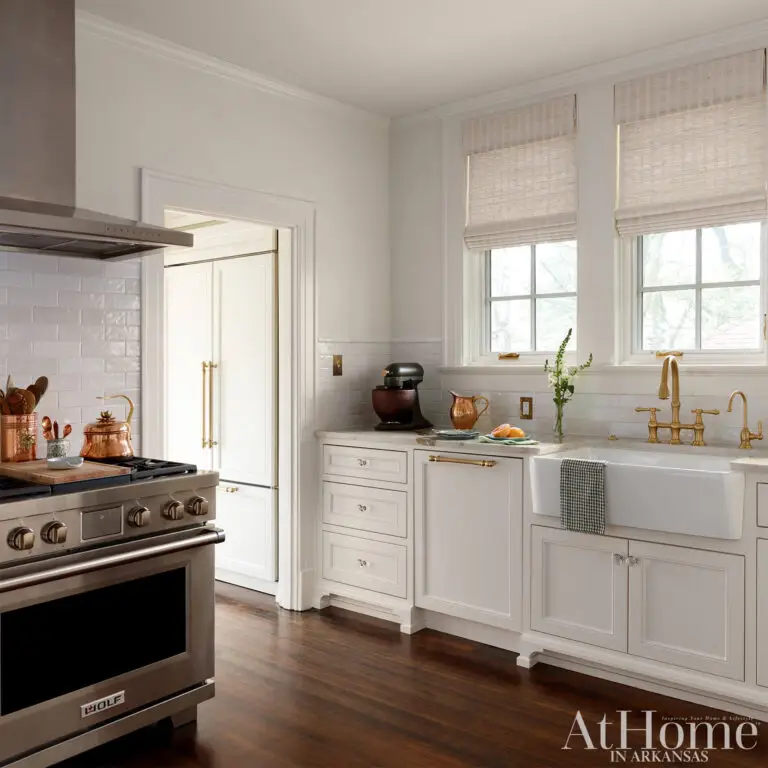 Classic white kitchen with marble countertops, farmhouse sink, brass fixtures and stainless steel range